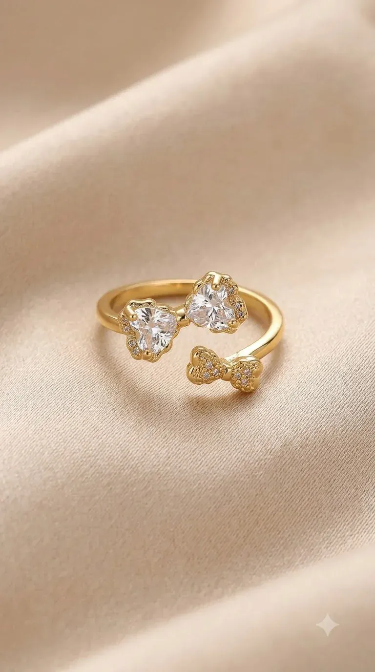 Gold adjustable bow ring with heart-cut crystal stones on beige satin