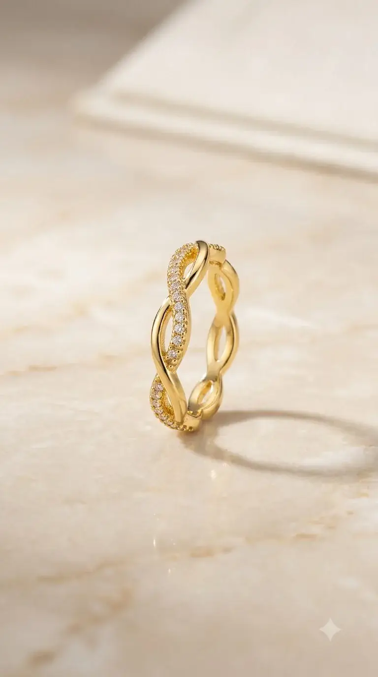 Slim gold infinity twist ring with pavé crystals on a marble step