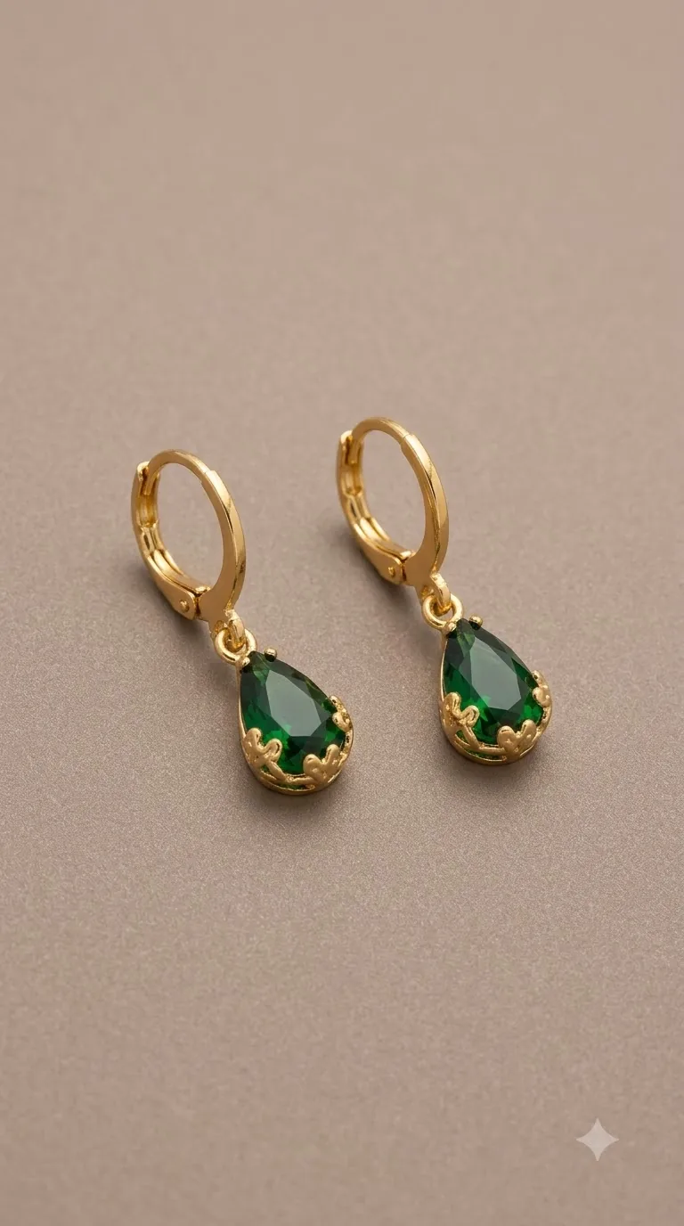 Gold-tone huggie hoop earrings with emerald-green teardrop stones in a crown setting