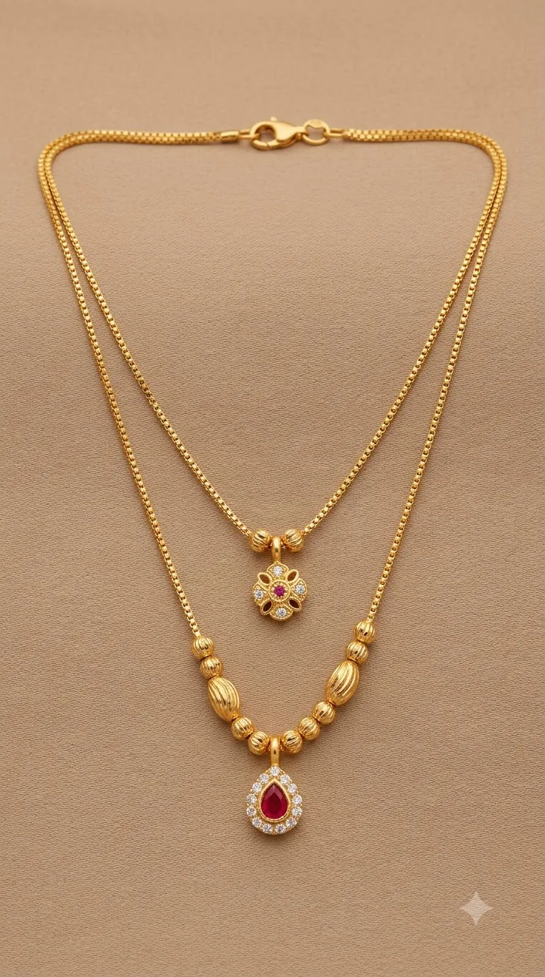 Two-layer gold-tone necklace with a ruby floral pendant and a ruby teardrop pendant on fluted gold beads