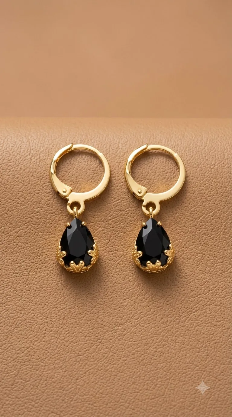 Gold-tone huggie hoop earrings with black teardrop stones in a crown setting
